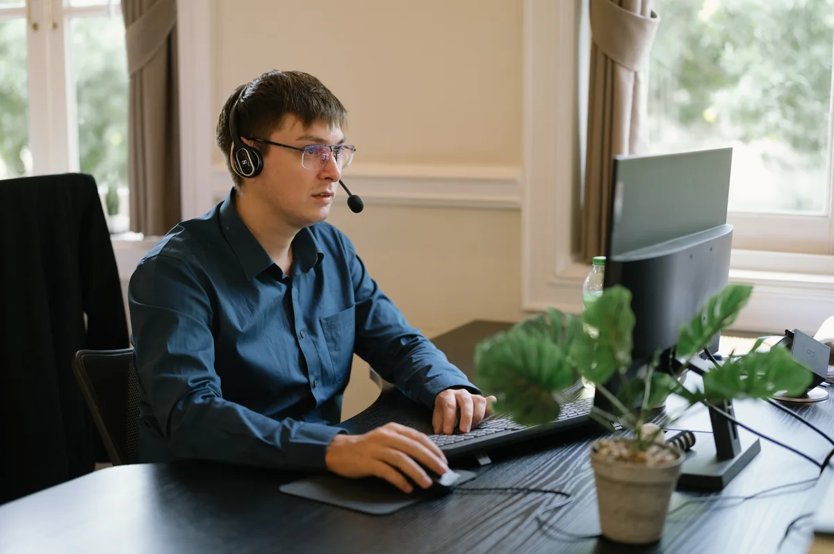 En supportmedarbejder med headset arbejder ved en computer