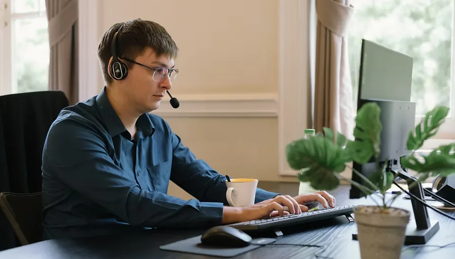 En MyData-tekniker med headset hjælper en kunde ved hans computer